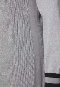 Grauer gestrickter Pullover mit einem strukturierten Muster, glatten Abschnitten und Navy-Streifen an den Bündchen. Hergestellt aus weichem Material mit einem lockeren Schnitt.