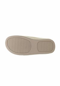 Zool van een slipper, met een lichtbruine rubberen basis met textured grips en een off-white fuzzy bovenrand. Rond vormen.