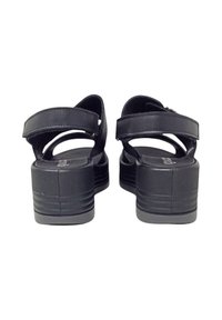 Sandali piattaforma neri con due cinturini regolabili, una suola texturizzata e una finitura in pelle liscia. Presentano una punta rotonda e un tacco rialzato.