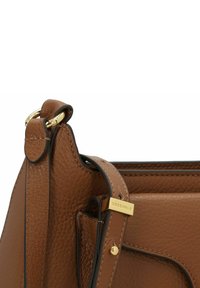 Bolso de mano de cuero marrón con acabado texturizado, herrajes dorados y costuras visibles. Cuenta con una correa corta y una etiqueta de marca en relieve.