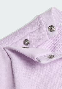 Cuello de camisa de algodón lila con botones a presión plateados. Tela suave y texturizada con un diseño acanalado distintivo cerca de los botones.