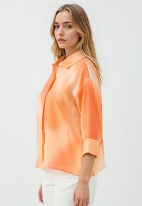 Leichtes, knöpfbares Hemd in graduierten Orangetönen. Verfügt über einen klassischen Kragen, aufrollbare Ärmel und eine glatte, semi-transparente Textur.