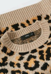 Pull beige avec un motif léopard en noir et orange. Présente un col côtelé et une texture douce. Étiquette de la marque visible.