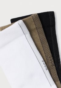 Tre par sokker: hvite, brune med et teksturert mønster, og svarte, med varierte strikke- og stoffteksturer.