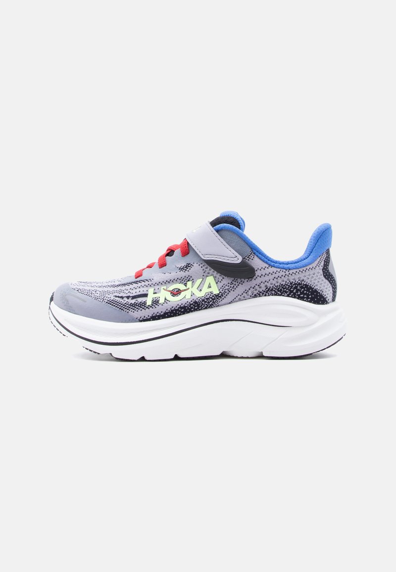 Zapatilla de running Hoka en gris y negro con cordones rojos, interior azul, suela blanca gruesa y una correa de velcro gris sobre un fondo blanco.