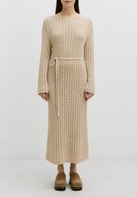 Beige gestricktes Kleid mit langen Ärmeln, gerippter Textur, runder Ausschnitt und einem passenden Gurt am Taillenbund. Bodenlanges Design.