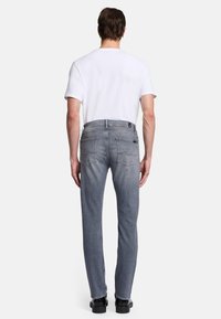 Vaqueros grises con un corte recto, diseño de cinco bolsillos y detalles de costura sutiles, combinados con una camiseta blanca lisa y zapatos negros.