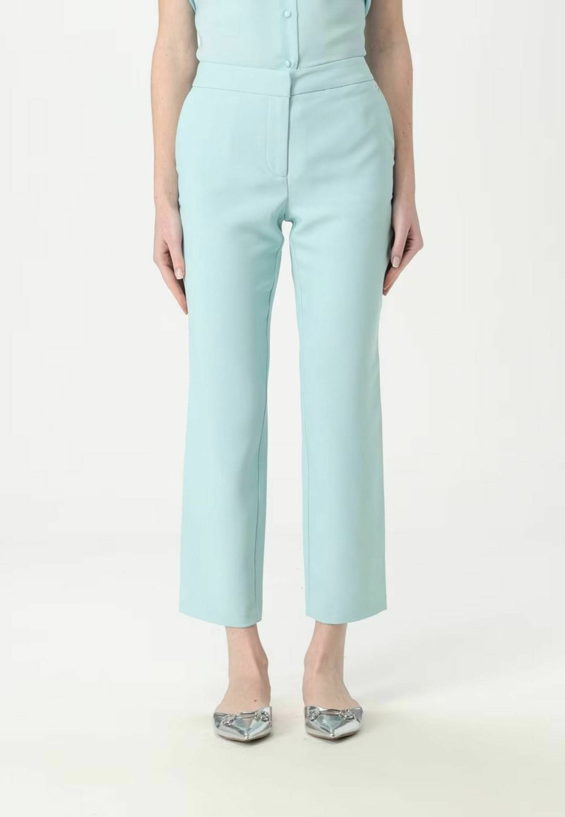 Pantaloni alti color verde menta con una vestibilità sartoriale, caratterizzati da una gamba dritta e cuciture laterali sottili. Abbinati a ballerine argentate.