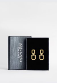 Guldörhängen med en geometrisk kedjelänkdesign, prydda med klara rhinestones, presenterade i en svart sammetspresentlåda.