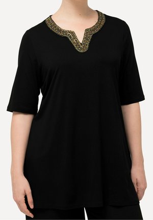 Czarna tunika z rękawami do łokcia i dekoltem w kształcie litery V zdobionym złotymi i wielokolorowymi koralikami, noszona przez osobę.