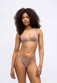 Vaaleanruskea bikinit-setti, jossa on pehmustettu kolmionmuotoinen rintaliivi säädettävillä olkaimilla ja yhteensopivat matalat alaosat, joissa on logotieto. Sujuva pinta.