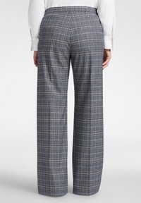 Geruite broek in marineblauw en grijs, met wijde pijpen en een getailleerde pasvorm. De stof heeft een zachte textuur met een subtiel ruitpatroon.