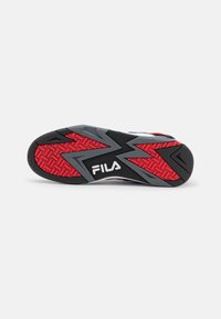 Suela de zapato atlético negra y roja con goma texturizada, patrón en zigzag y logotipo blanco de "FILA" centrado en la punta.