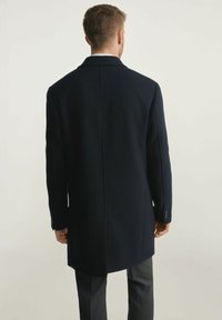 Granatowy wełniany płaszcz o dopasowanym kroju, jednorzędowy design, klapy z wycięciem oraz mankiety zapinane na trzy guziki, pokazany z tyłu.