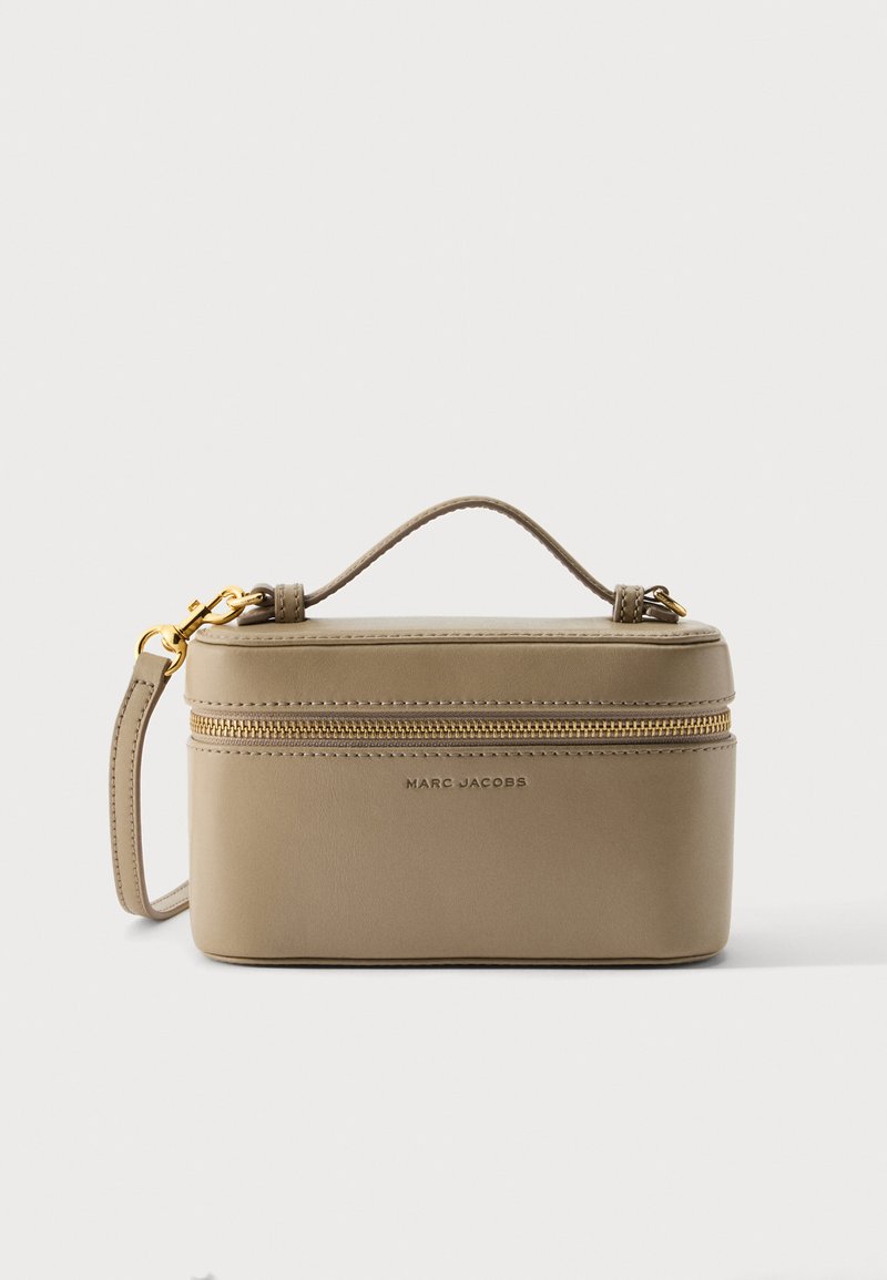 Μπεζ ορθογώνια τσάντα χειρός Marc Jacobs με πάνω χερούλι, χρυσό φερμουάρ και αποσπώμενο λουράκι, σε απλό λευκό φόντο.