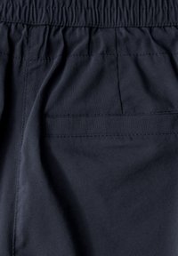 Marineblaue Stoff mit weicher Textur, ausgestattet mit einem elastischen Bund und einer kleinen, horizontalen Gesäßtasche. Sichtbare Steppnähte.