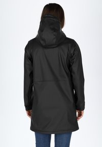 Svart vattentät kappa med huva, långa ärmar och rak skärning. Har en slät yta och en minimalistisk design utan synlig hårdvara.