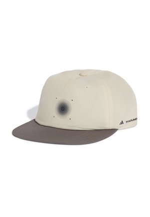 Casquette de baseball couleur crème avec une visière gris foncé, présentant un motif circulaire de points à l'avant et un petit logo sur le côté.