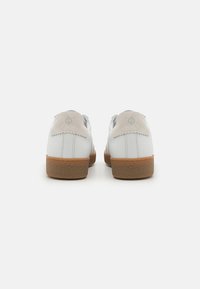 Scarpe bianche in pelle con un tallone in suede beige, forma rotonda, suola in gomma testurizzata e logo discreto sul retro.