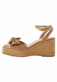 Braune Wildleder-Plateau-Wedgesandalen mit verstellbarem Knöchelriemen, offener Zehenpartie und einer dekorativen Schleife auf der Vorderseite. Mit geflochtenen Jute-Details.