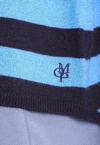 Neulottu pusero, jossa on vuorottelevat vaaleansiniset ja tummansiniset raidat. Helmassa pieni tummalla langalla kirjailtu logo.