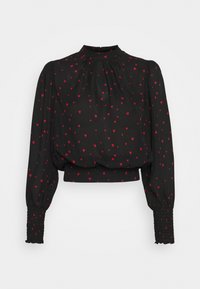 Blouse noire à manches longues avec motif de cœurs rouges, col haut, épaules froncées et poignets smockés.