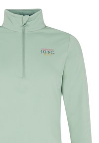 Jasnozielony sweter z długim rękawem i zamkiem na szyi, z napisem "LET'S GO SKIING PROTEST" wydrukowanym w miękkich pastelowych kolorach na klatce piersiowej.