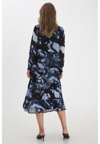 Vestido azul y negro en capas con mangas largas, hecho de una tela ligera con un patrón abstracto y una silueta fluida.