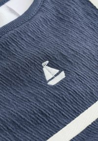 Marineblå bomulds-T-shirt med struktureret finish, hvidt sejlbåd broderi og en kontrasterende hvid stribe ved halsåbningen.