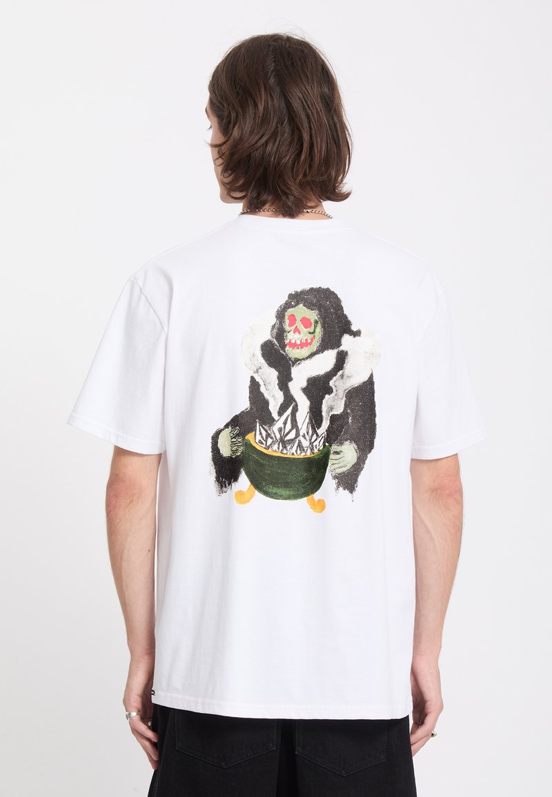 Personne portant un t-shirt blanc avec un graphisme coloré au dos représentant un squelette encapuchonné tenant un chaudron vert fumant.