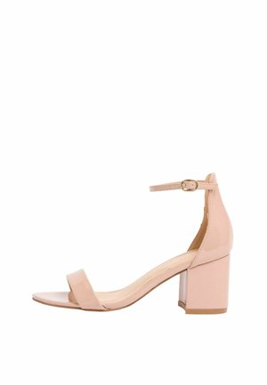 Sandaľ na blokovom opätku z lakovanej kože v telovej farbe s remienkom okolo členka a zlatou prackou, otvorenou špičkou a nízkym, masívnym opätkom.