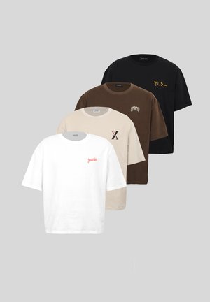 Dos modelos llevan camisetas beige oversize con un pequeño logo, uno con pantalones cortos negros y zapatillas, el otro con pantalones marrones y zapatos negros.