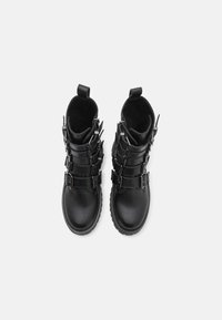 Black leather boots with a smooth texture, featuring multiple metallic buckles and a stitched sole, designed with a tall cut and pull tab.