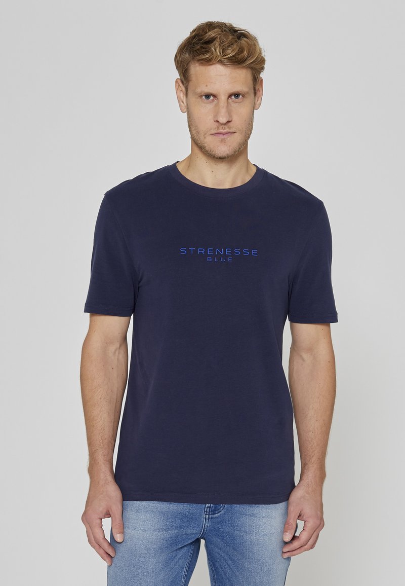 T-shirt en coton bleu marine avec col rond et manches courtes, mettant en avant le logo "STRENESSE" en bleu sur le devant.
