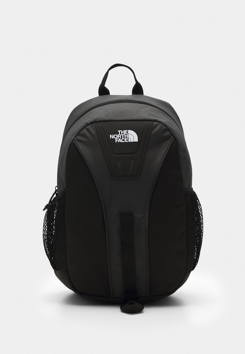 Sac à dos North Face noir et gris foncé avec logo sur le devant, poches latérales en mesh et poignée de transport supérieure, présenté sur un fond uni.