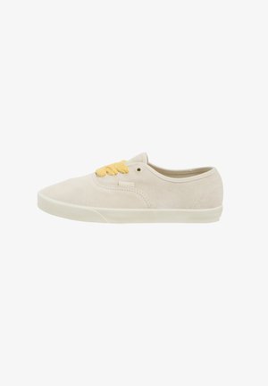 Zapatillas de ante beige con un diseño de caña baja, que presentan cordones amarillos, punta redonda y una suela de goma plana. Estilo limpio y minimalista.