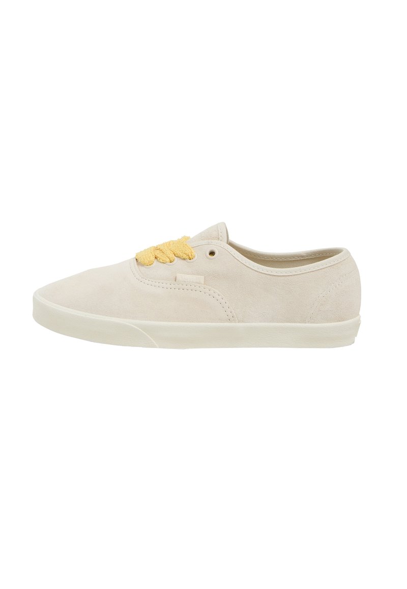 Beige suede sneakers with a low-top design, featuring yellow laces, round toe, and a flat rubber sole. Clean, minimalist style.