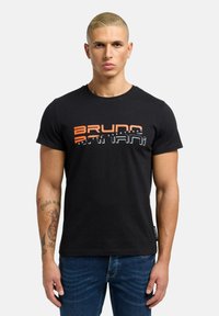 Sort bomulds t-shirt med iøjnefaldende grafisk tekst i orange og hvid. Korte ærmer, rund hals og et mærke i kanten. Denim jeans synlige.