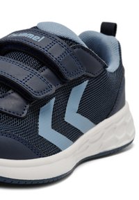 Blå nät sneakers med marinblå accenter, utrustade med två blå chevronränder, kardborreband och en vit texturerad sula.