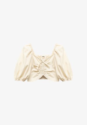 Kermakolorinen lyhyt paita puff-hihalla, kerätyllä bodysuunnittelulla ja hillityillä pystyriveillä. Siinä on neliömäinen pääntie ja säätönyöritys.