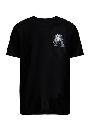 T-shirt noir à manches courtes avec une grande lettre "A" ornée de motifs floraux détaillés en blanc et gris sur le côté supérieur gauche de la poitrine.