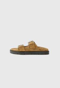 Sandale slide din suede maro, cu două curele reglabile cu catarame, un brant căptușit și o talpă din cauciuc negru cu un model texturat.