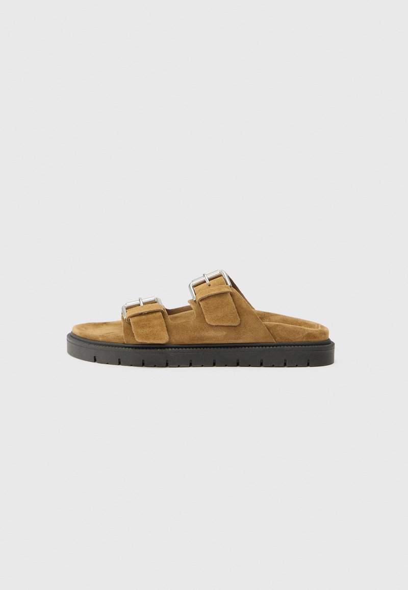 Brown suede slide sandals with two adjustable buckle straps, a cushioned footbed, and a black rubber outsole with a textured pattern.