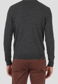 Pull gris à manches longues, col rond, avec des poignets et un ourlet côtelés, fabriqué en matériau tricoté doux. Porté par-dessus un pantalon marron.