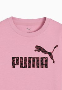 Rožinė medvilninė marškinė su tamsiu leopardiniu raštu ir "PUMA" logotipu bei šuoliuojančio pumos grafika panašiomis spalvomis. Apvalus kaklas, trumpomis rankovėmis.