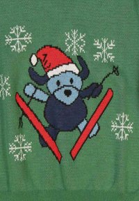 Grön tröja med en animerad blå hund som bär en röd tomteluva, som åker skidor på röda skidor med vita snöflingor i bakgrunden.
