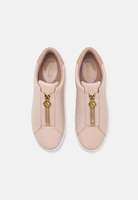 Sneakers slip-on rosa chiaro con texture a trapunta, dotate di una cerniera dorata e un logo accentuato. Parte superiore in pelle liscia e suola in gomma bianca.