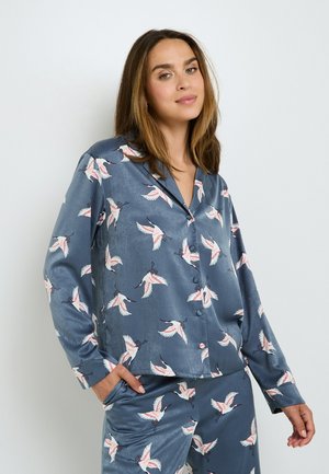 Haut de pyjama en satin de couleur bleu muted avec un motif de grues blanches et roses, fermeture à boutons sur le devant, et manches longues avec une coupe décontractée.