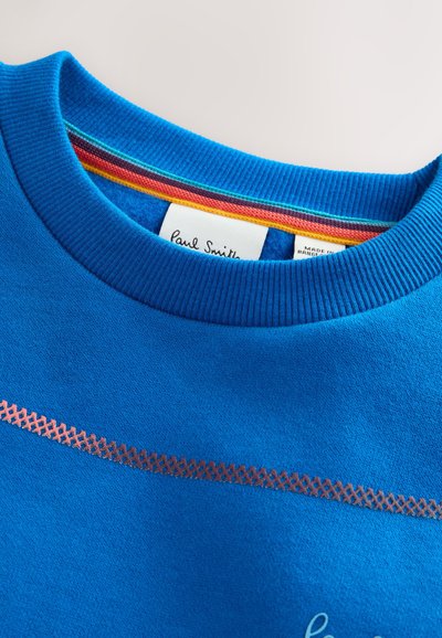 Blue crewneck sweatshirt with ribbed collar, rainbow-striped inner neck detail, and a small embroidered design near the chest area.