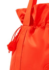 Röd nylon dragsnörsöppnad väska med en samlad topp, utrustad med en gummibjörnsformad dragkedjeöppnare och en mjuk, slät textur.